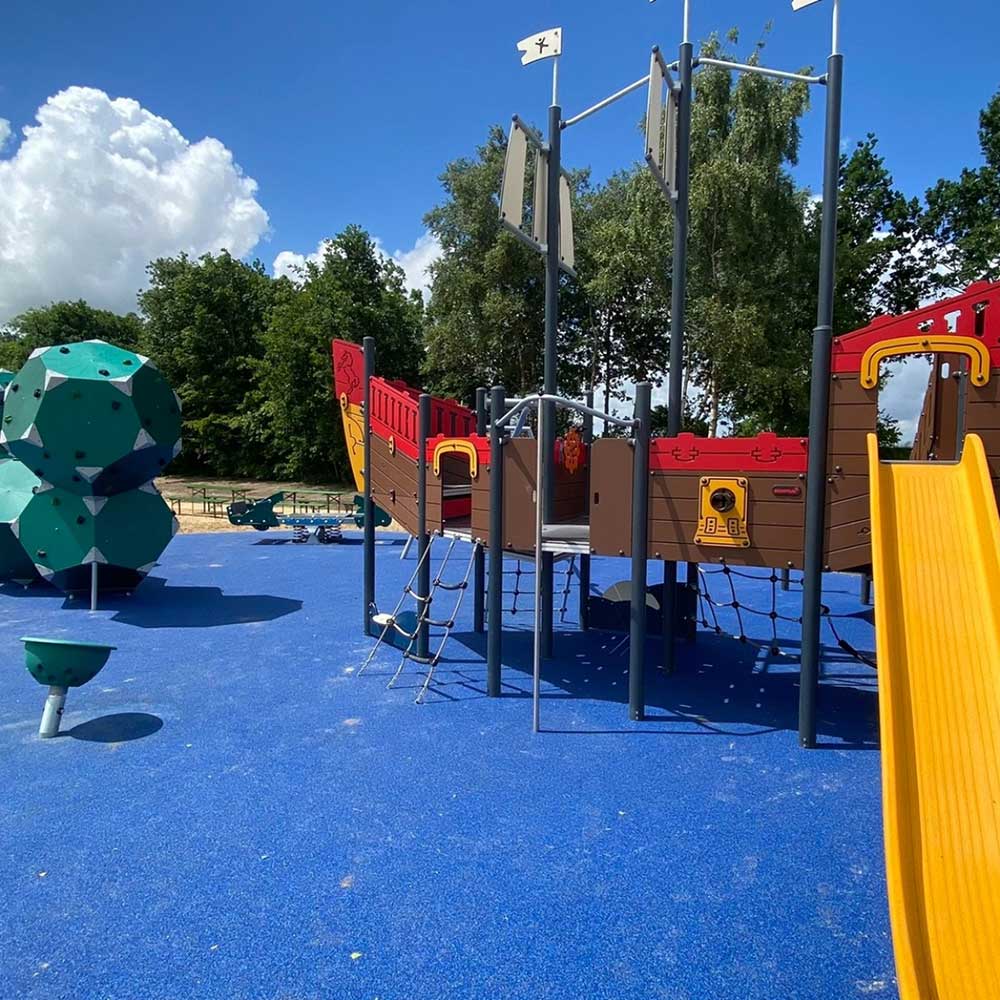 Großes Kletterschiff auf blauem barrierefreien Fallschutz auf dem inklusiven Spielplatz TImmeler Meer