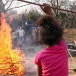 Ein Mädchen sitzt am großen Lagerfeuer auf einem Abenteuerspielplatz